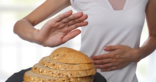 Woman holding her stomach while standing next to a loaf of bread